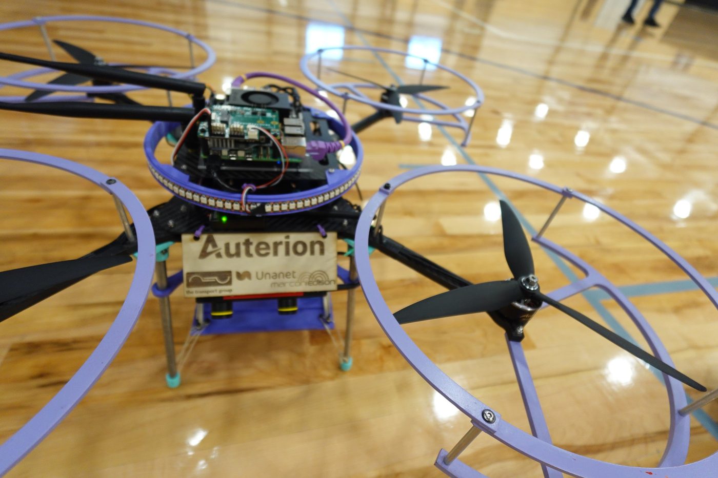 Close view of a ducted competition quadcopter showing its exposed flight controller and companion computer under the top plate.