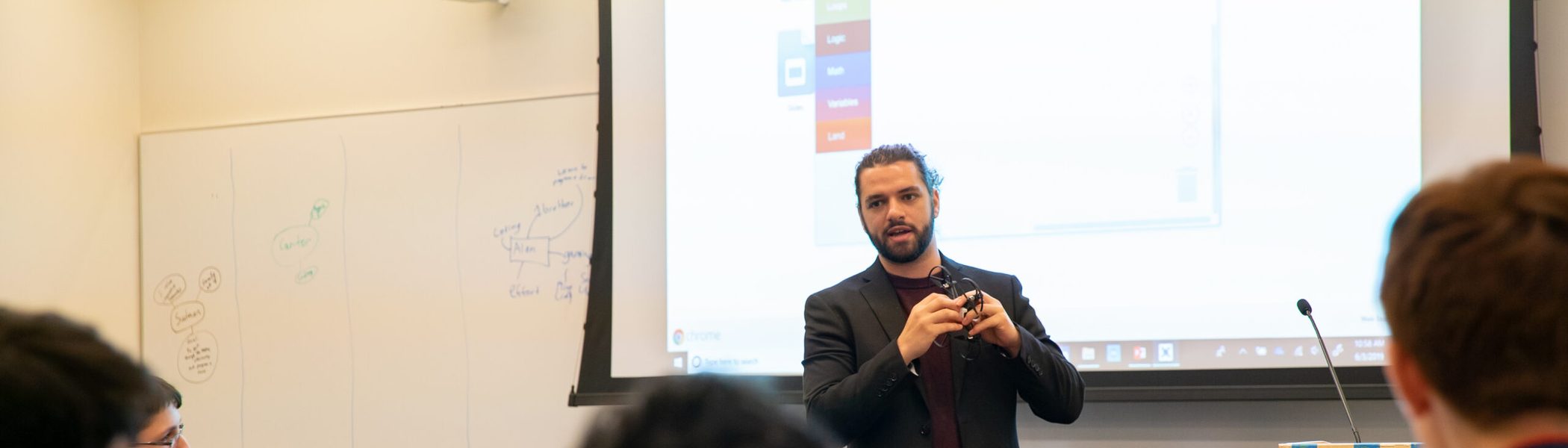 A DroneBlocks presenter on stage addressing a seated audience at a Microsoft Discovery Day event.